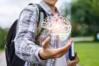 Etudiant portant chemise, un livre dans une main et un sac-à-dos sur une épaule tenant un holograme de cerveau dans l'autre main
